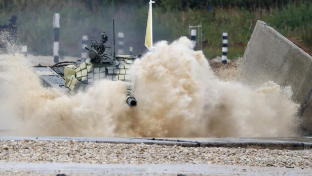 Ein Panzer durchfährt ein Wasserhindernis, wobei viel Wasser aufspritzt.