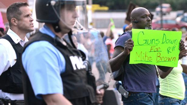 Ein Mann hält ein Schild mit der Aufschrift „Guns Down for RIP Mike Brown“ bei einer Demonstration.