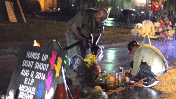 Im Regen gedenken zwei Männer Michael Brown an einer improvisierten Gedenkstätte.