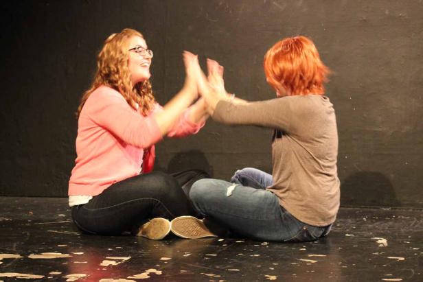 Zwei Frauen sitzen einander gegenüber und klatschen in die Hände.