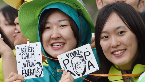 Zwei junge Frauen halten Schilder mit der Aufschrift „Keep Calm and Viva Papa!“ und „Viva el Papa!".
