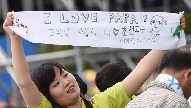 Eine Frau hält ein Banner mit der Aufschrift „I love Papa“ und koreanischen Schriftzeichen hoch.