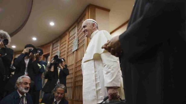 Papst Franziskus lächelt umgeben von Fotografen.