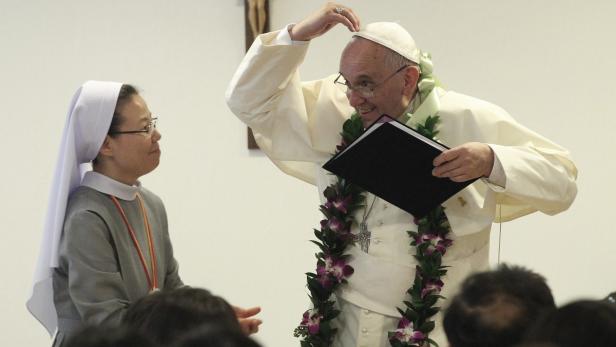 Papst Franziskus mit Blumenkranz und einer Ordensschwester.