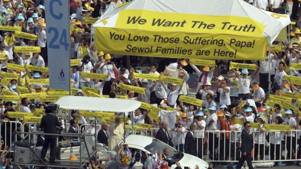 Eine Menschenmenge demonstriert mit gelben Schildern und Bannern für die Familien der Sewol-Opfer.