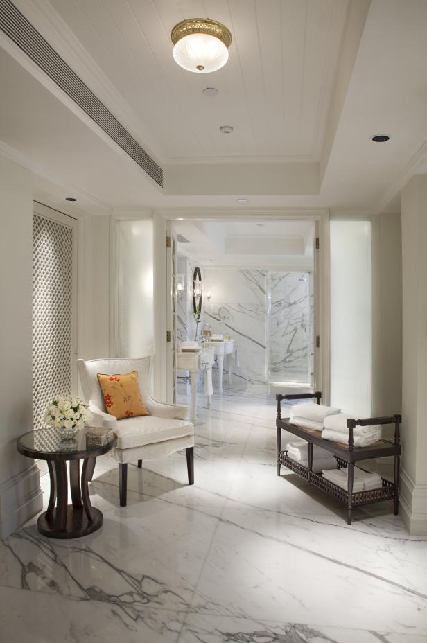 Ein luxuriöses Badezimmer mit Marmorboden und einem Sessel mit Blumenkissen.