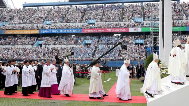 Papst Franziskus leitet eine Messe in einem Stadion vor einer großen Menschenmenge.