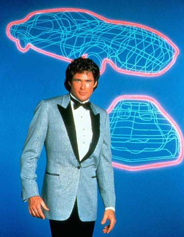 David Hasselhoff im Smoking vor einem blauen Hintergrund mit Neon-Auto-Umrissen.