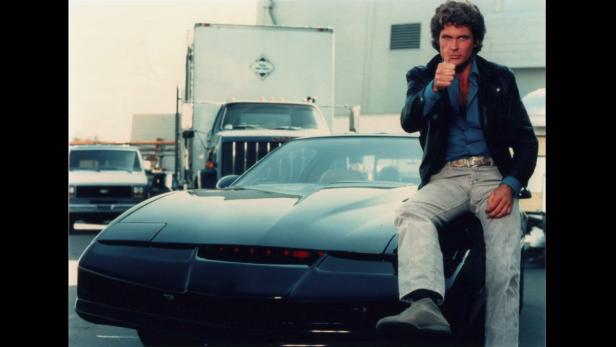 David Hasselhoff sitzt auf dem Auto K.I.T.T. aus der Serie „Knight Rider“.