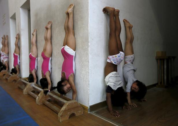 Mehrere junge Turnerinnen machen Handstandübungen an einer Wand.