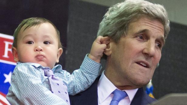 Ein Baby zieht an John Kerrys Ohr.