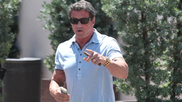 Sylvester Stallone mit Sonnenbrille und Zigarre in der Hand.