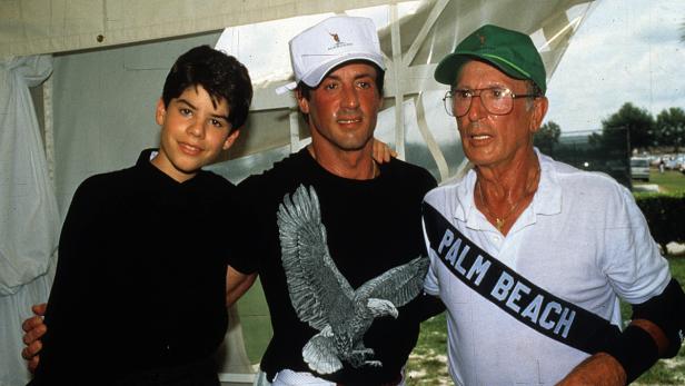 Sylvester Stallone mit einem Jungen und einem älteren Mann, alle tragen Kappen, posieren für ein Foto.