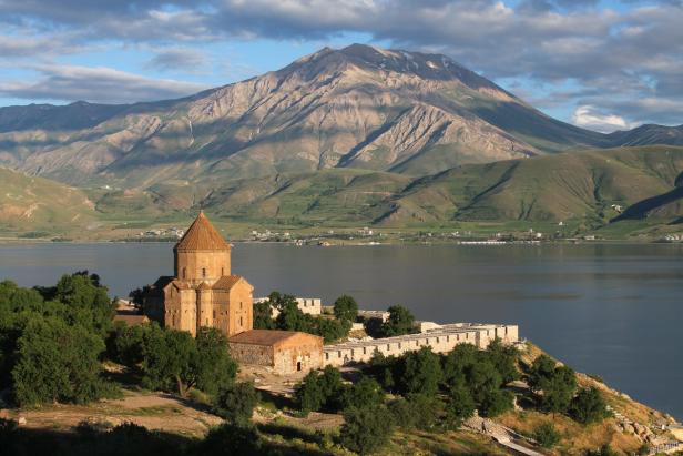 Die armenische Heiligkreuzkirche von Akdamar am Vansee vor einer Bergkulisse.