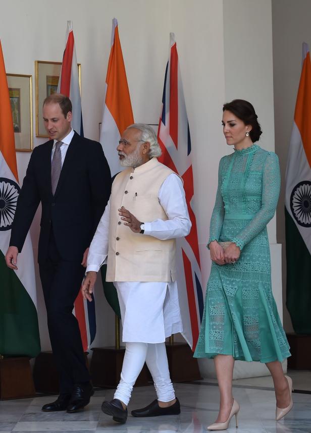 Prinz William, Narendra Modi und Kate Middleton gehen vor Flaggen entlang.