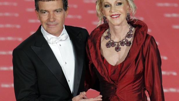 Antonio Banderas und eine Frau in einem roten Kleid posieren auf einem roten Teppich.