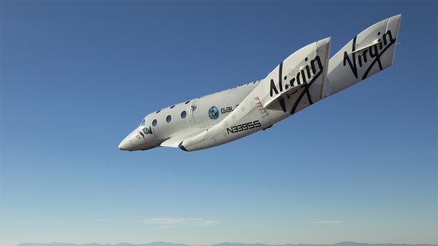 Das Raumschiff „Virgin Galactic“ fliegt vor blauem Himmel.