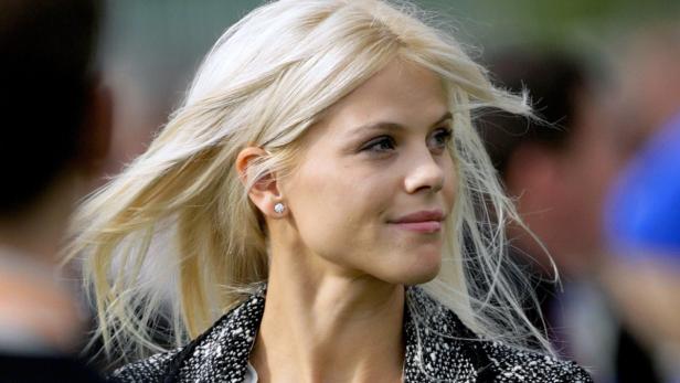 Eine Frau mit blonden Haaren und Ohrringen blickt zur Seite.
