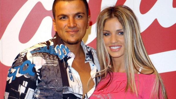 Peter Andre und Katie Price posieren vor einem roten Hintergrund.