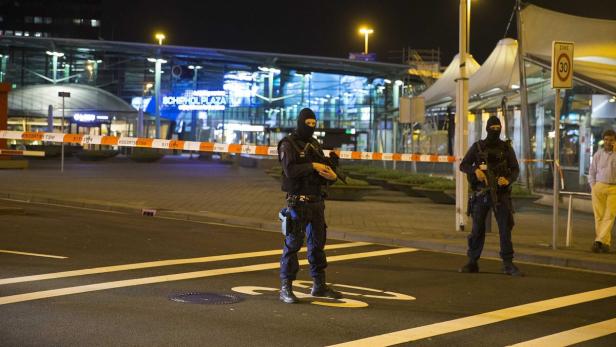 Zwei Polizisten mit Sturmhauben stehen vor dem Schiphol Plaza, abgesperrt mit einem rot-weißen Band.