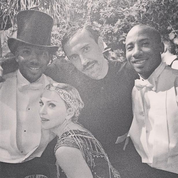 Madonna mit drei Männern, gekleidet im Stil der 1920er Jahre, posiert für ein Foto.