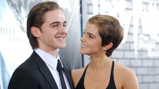 Emma Watson und ein junger Mann lächeln sich an.