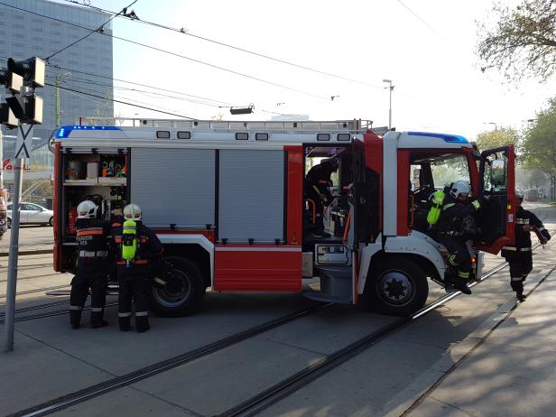 Feuerwehrleute steigen in ein rotes und graues Feuerwehrauto.