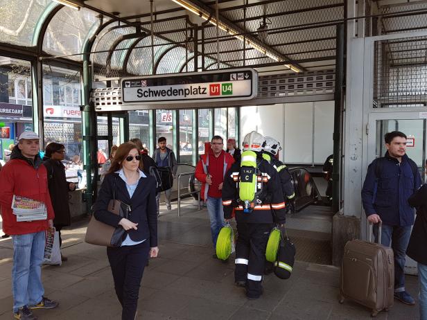 Menschen und zwei Feuerwehrleute am U-Bahnhof Schwedenplatz in Wien.