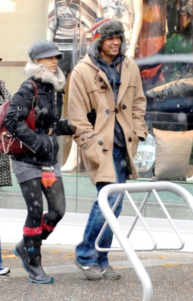 Ein Paar geht im Winter in warmer Kleidung an einem Schaufenster vorbei.