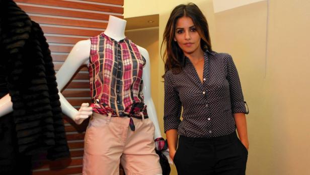 Eine Frau posiert neben einer Schaufensterpuppe mit karierter Bluse und Shorts.