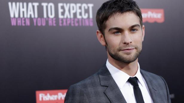 Chace Crawford posiert vor dem Filmplakat „Was Sie erwartet, wenn Sie ein Kind erwarten“.