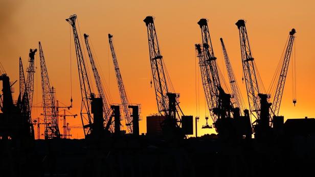 Silhouette von Kränen in einem Hafen bei Sonnenuntergang.