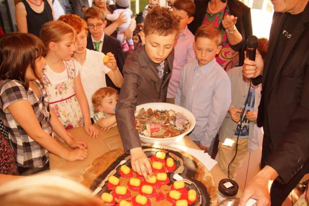 Eine Gruppe Kinder dekoriert gemeinsam einen Kuchen mit Süßigkeiten.