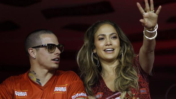 Jennifer Lopez und ein Mann in einem roten T-Shirt winken in die Menge.