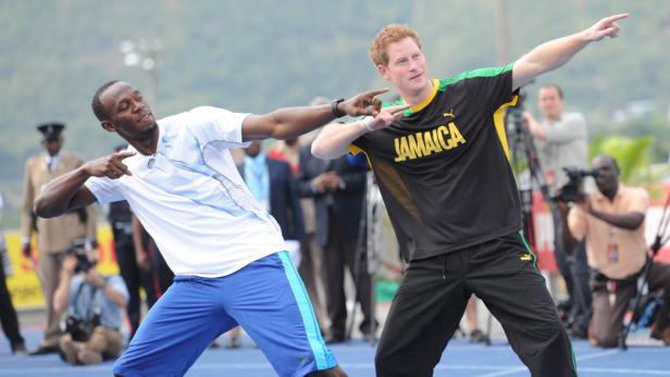 Usain Bolt und Prinz Harry posieren auf einer blauen Laufbahn.