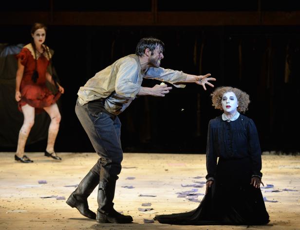 Szene aus einem Theaterstück mit drei Schauspielern in Kostümen und weißer Schminke.