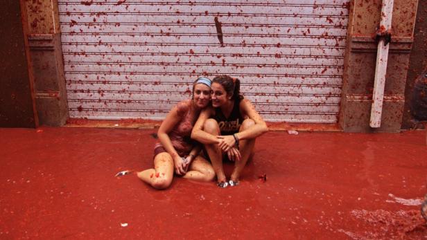 Zwei Frauen sitzen während der Tomatina in Buñol im Tomatenpüree.