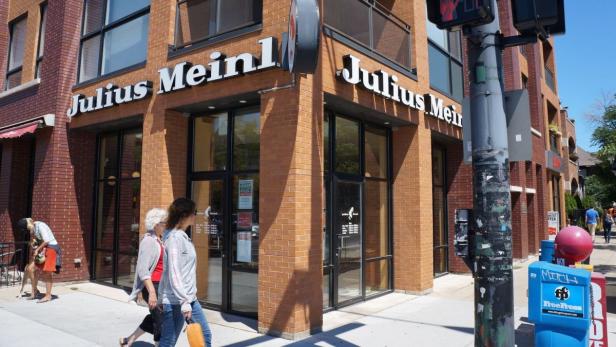 Das Geschäft „Julius Meinl“ an einer Straßenecke mit Passanten.