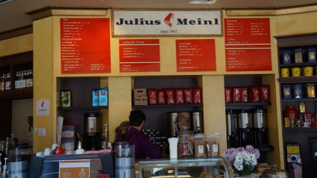 Innenansicht eines Julius Meinl Cafés mit Menüs und Kunden.