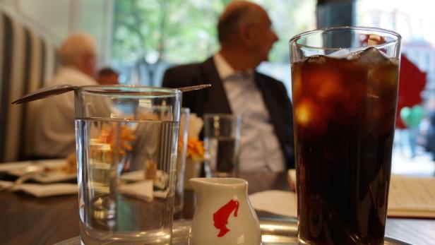 Ein Glas Eiskaffee und ein Glas Wasser stehen auf einem Tisch in einem Café.