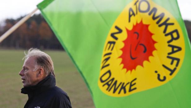 Ein Mann steht neben einer grünen Flagge mit der Aufschrift „Atomkraft? Nein Danke“.