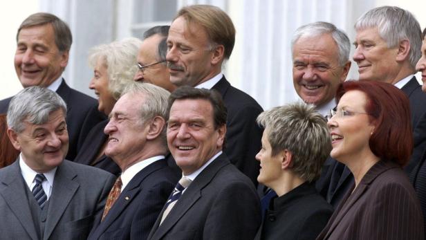 Eine Gruppe von lächelnden Personen in Anzügen steht zusammen.