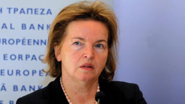 Eine Frau mit blonden Haaren und einer Perlenkette spricht in ein Mikrofon.