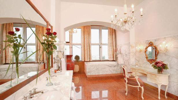 Ein luxuriöses Badezimmer mit Marmor, einem Kronleuchter und Rosen.