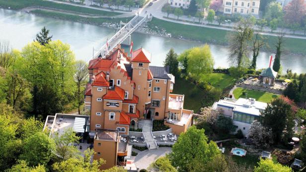 Luftaufnahme von Schloss Ort in Gmunden mit der Traun und einer Brücke im Hintergrund.