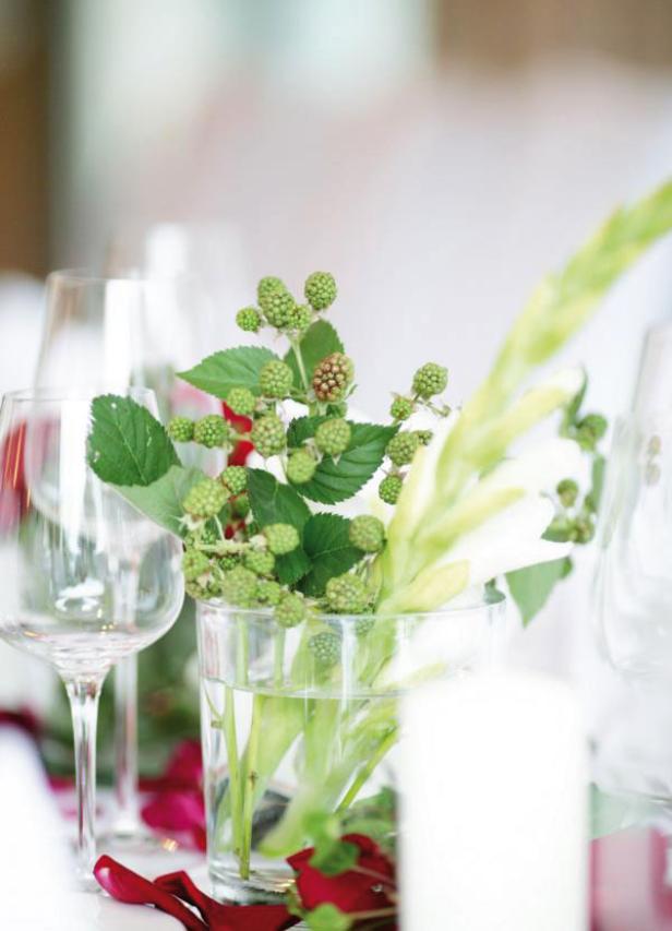 Ein Tisch mit einem Blumenarrangement aus Brombeeren und Gladiolen in einer Vase.