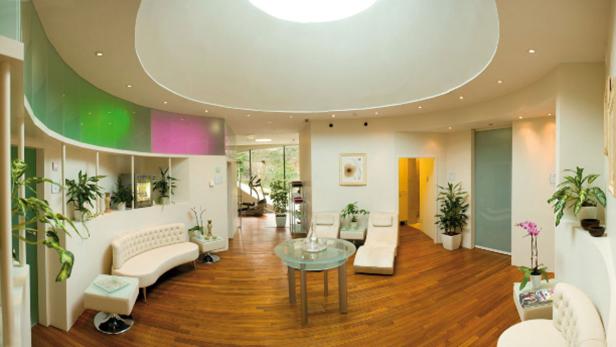 Ein heller, moderner Wartebereich mit weißen Möbeln und Holzboden.