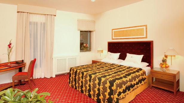 Ein Hotelzimmer mit einem Doppelbett, einem Schreibtisch und einem roten Teppich.