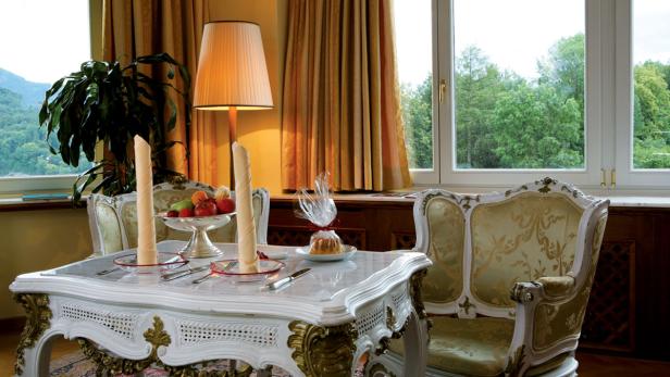 Ein reich gedeckter Tisch mit Obstschale, Gebäck und gerollten Servietten in einem eleganten Raum.