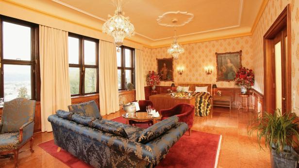 Ein luxuriöses Hotelzimmer mit Antiquitäten, Kristalllüstern und einem großen Fenster mit Ausblick.